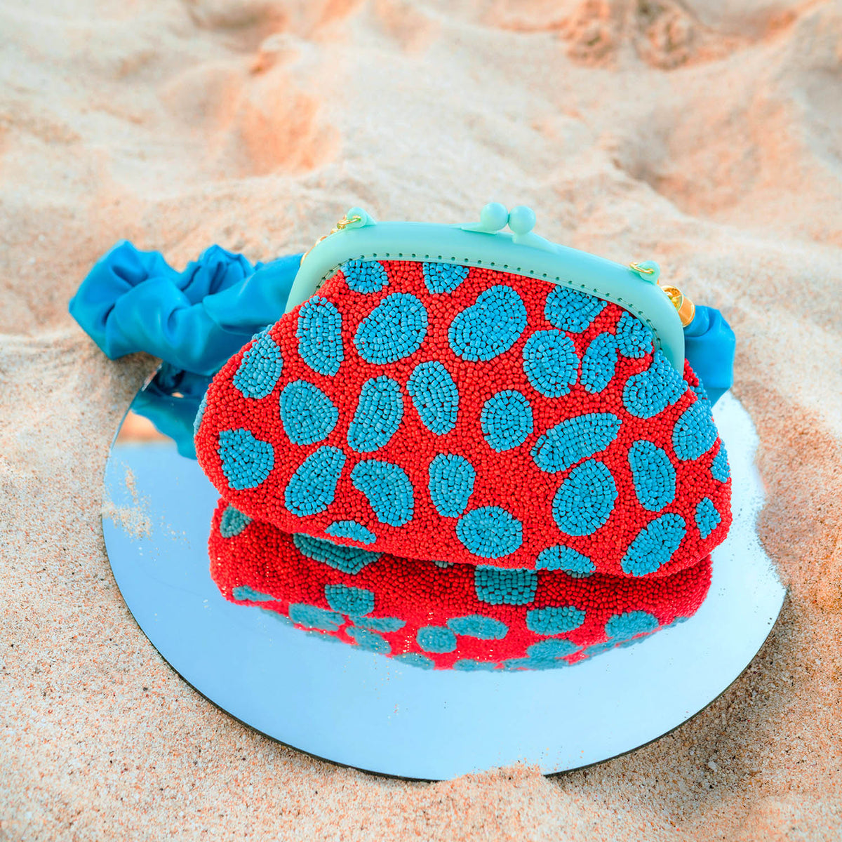 BrunnaCo Arnoldi Ariela Handbeaded clutch in red and turquoise blue color is an artisanal handmade piece by female artisans in Bali. This handbag clutch is carefully and sustainably made using glass beads in playful polka dot pattern.