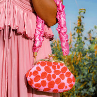 BrunnaCo Arnoldi Daisy Hand-beaded clutch bag in bright pink and red color, designed in California, handmade in Bali. This artisanal clutch bag has an adorable scrunched handle in Barbie pink color