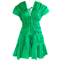 A woman is wearing SRIKANDI Ruffle Cotton Dress In Kelly Green at the tropical beach in Cannes, France Bingin Bali