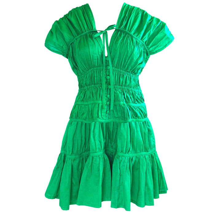 A woman is wearing SRIKANDI Ruffle Cotton Dress In Kelly Green at the tropical beach in Cannes, France Bingin Bali