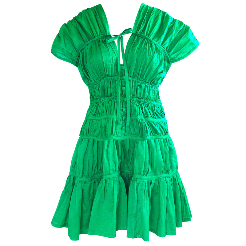 A woman is wearing SRIKANDI Ruffle Cotton Dress In Kelly Green at the tropical beach in Cannes, France Bingin Bali