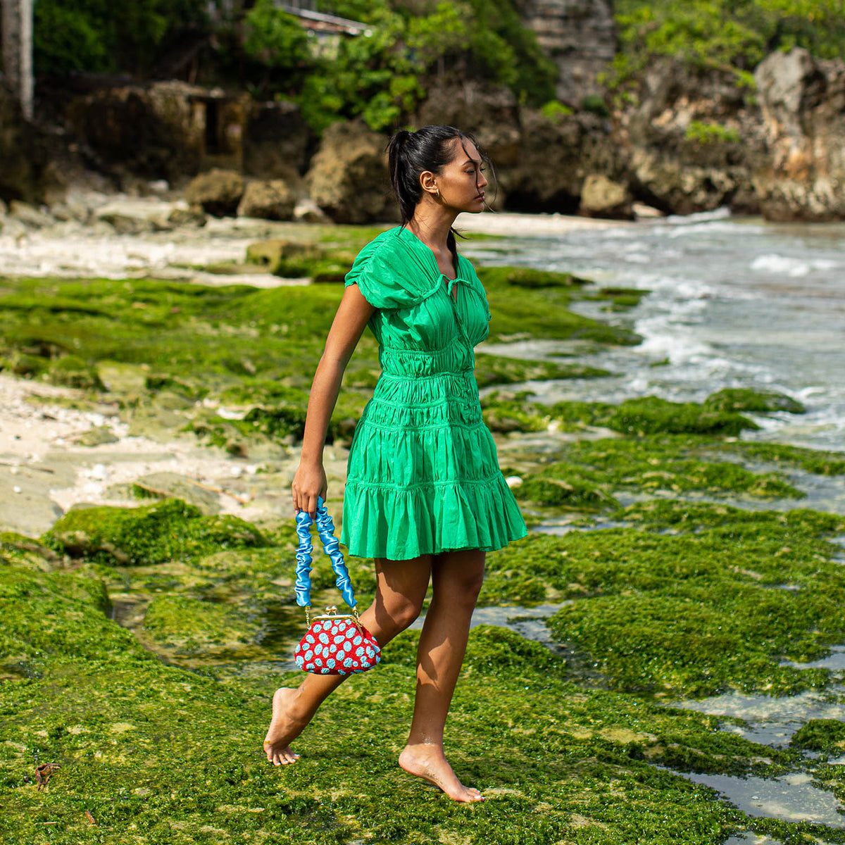 A woman is wearing SRIKANDI Ruffle Cotton Dress In Kelly Green at the tropical beach in Cannes, France Bingin Bali
