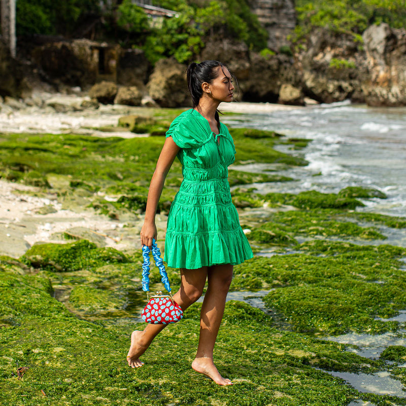 A woman is wearing SRIKANDI Ruffle Cotton Dress In Kelly Green at the tropical beach in Cannes, France Bingin Bali