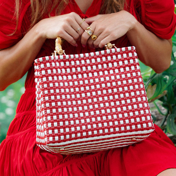 Inka Williams carries BrunnaCo's TUKU Recycled Plastic Market Tote, a handcrafted piece from Java and Bali made from repurposed plastic waste. Designed in California, it embodies the effortless charm of a California farmers' market.