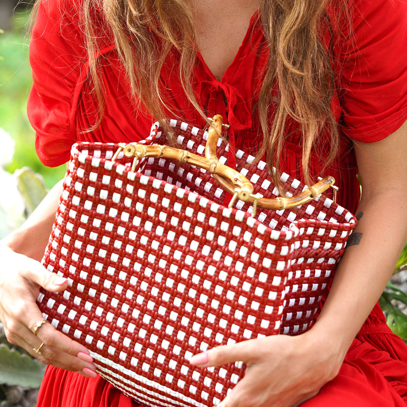 Inka Williams carries BrunnaCo's TUKU Recycled Plastic Market Tote, a handcrafted piece from Java and Bali made from repurposed plastic waste. Designed in California, it embodies the effortless charm of a California farmers' market.