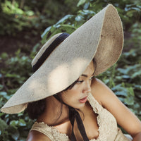 Lola Wide Brim Jute Straw Hat with Black Strap. Braided meticulously by artisans in Gianyar, Bali from natural Jute material, this sweet hat offers both comfort and elegance. Designed with ideal thickness and weight that allow its brim to be easily folded, stretched, and styled, making it easy to take to any holiday trips.