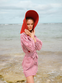 BrunnaCo Lola Wide Brim Jute Straw Hat in Red. A wide-brimmed straw hat in a vibrant red color. The hat is made from natural jute fibers and features a comfortable inner lining. It is perfect for sun protection and style. Handmade by women artisans in Bali, Indonesia