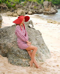 BrunnaCo Lola Wide Brim Jute Straw Hat in Red. A wide-brimmed straw hat in a vibrant red color. The hat is made from natural jute fibers and features a comfortable inner lining. It is perfect for sun protection and style. Handmade by women artisans in Bali, Indonesia