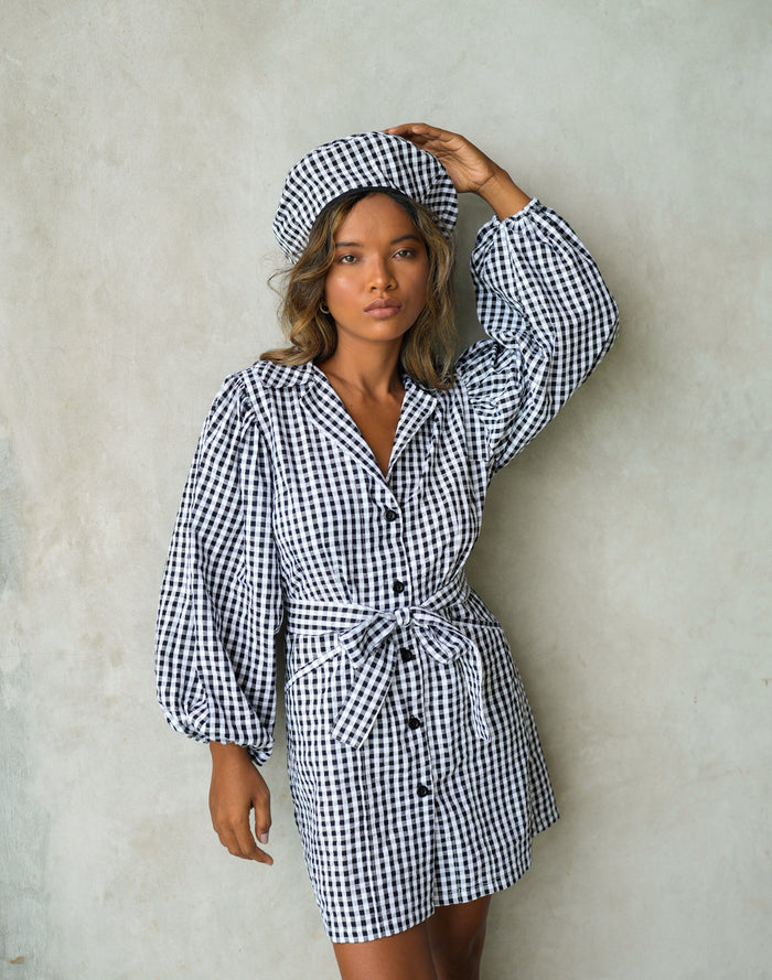 BrunnaCo Meghan Mini Gingham Dress in Black - A stylish and versatile dress made from 100% cotton. This dress features a sweet silhouette with voluminous medium-length puff sleeves, a chic short skirt with bow-detailing, and a removable waist belt. The Meghan Mini Gingham Dress is perfect for any occasion, from a casual picnic to a formal event.