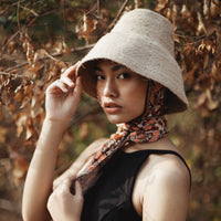 Naomi Jute Straw hat in Beige. Naomi Jute Bucket Hat is designed specifically for the wild at heart with classic sophistication. Enjoy lounging poolside or exploring the city on sun-soaked days as its protective hat brim provides ample shade. Made of natural jute straws which have the perfect weight, this hat will sit comfortably and won't fly away in sudden gusts. It's also very practical to pack in any size luggages and ideal to take on any trips.