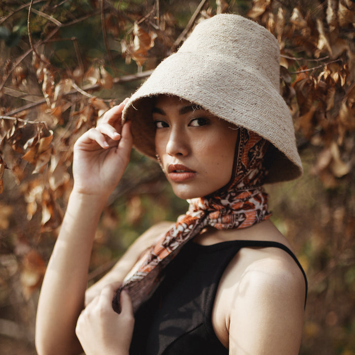 Naomi Jute Straw hat in Beige. Naomi Jute Bucket Hat is designed specifically for the wild at heart with classic sophistication. Enjoy lounging poolside or exploring the city on sun-soaked days as its protective hat brim provides ample shade. Made of natural jute straws which have the perfect weight, this hat will sit comfortably and won't fly away in sudden gusts. It's also very practical to pack in any size luggages and ideal to take on any trips.