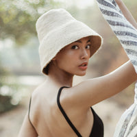 Naomi Jute Straw hat in Beige. Naomi Jute Bucket Hat is designed specifically for the wild at heart with classic sophistication. Enjoy lounging poolside or exploring the city on sun-soaked days as its protective hat brim provides ample shade. Made of natural jute straws which have the perfect weight, this hat will sit comfortably and won't fly away in sudden gusts. It's also very practical to pack in any size luggages and ideal to take on any trips.