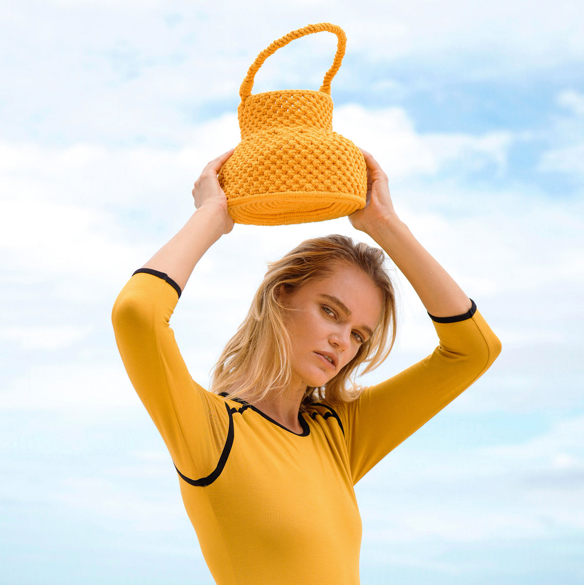 Olga is strolling by the shore with BrunnaCo's Petite Naga Macrame Beach Bag in Butter Yellow — the perfect companion for a sun-kissed summer day.