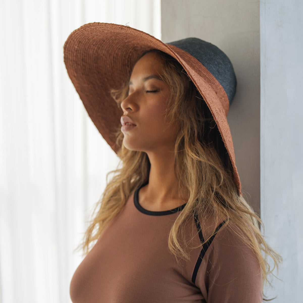 Duo color tone handwoven beach straw hat in Burnt Sienna and Black color, handmade from natural jute straw by local artisan in Bali. Handmade vacation wide-brim hat with domed down brim for maximum sun protection. Sustainably made by female artisan community in Indonesia.