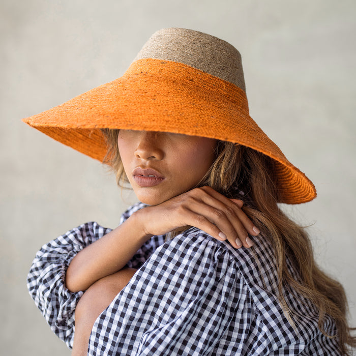 Duo color tone handwoven beach straw hat in natural and pumpkin orange color, handmade from natural jute straw by local artisan in Bali. Handmade vacation wide-brim hat with domed down brim for maximum sun protection. Sustainably made by female artisan community in Indonesia for resort vacation season.