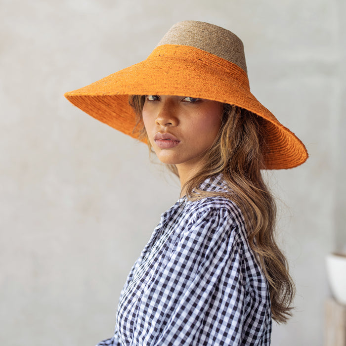 Duo color tone handwoven beach straw hat in natural and pumpkin orange color, handmade from natural jute straw by local artisan in Bali. Handmade vacation wide-brim hat with domed down brim for maximum sun protection. Sustainably made by female artisan community in Indonesia for resort vacation season.
