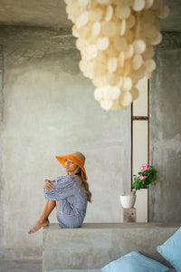 Duo color tone handwoven beach straw hat in natural and pumpkin orange color, handmade from natural jute straw by local artisan in Bali. Handmade vacation wide-brim hat with domed down brim for maximum sun protection. Sustainably made by female artisan community in Indonesia for resort vacation season.
